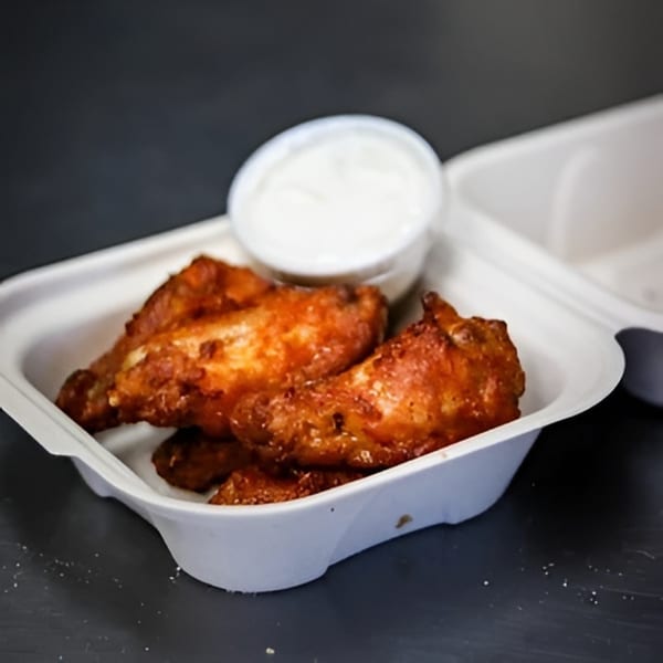 Valentino's Pizza PCH chicken wings with dipping sauce in a white takeout container.