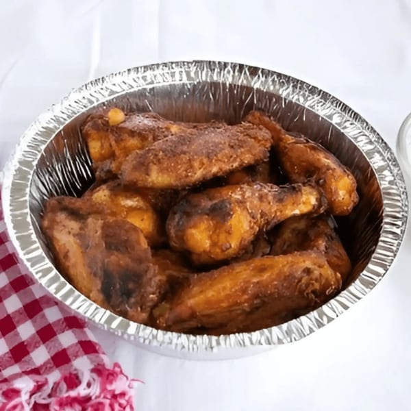 Valentino's Pizza PCH's crispy chicken wings in a foil container, with a red and white checkered napkin.