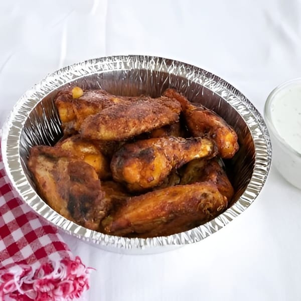 Valentino's Pizza PCH's baked chicken wings in a foil pan with a side of ranch dressing.