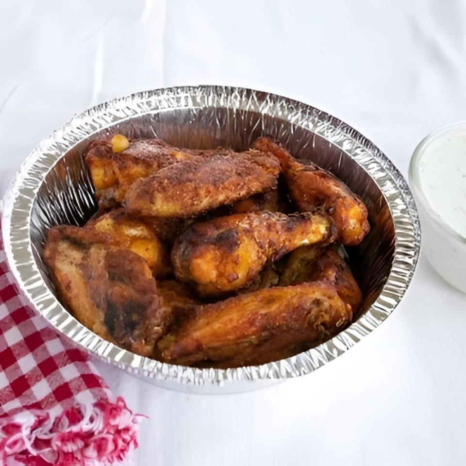 Valentino's Pizza PCH's baked chicken wings in a foil pan with a side of ranch dressing.